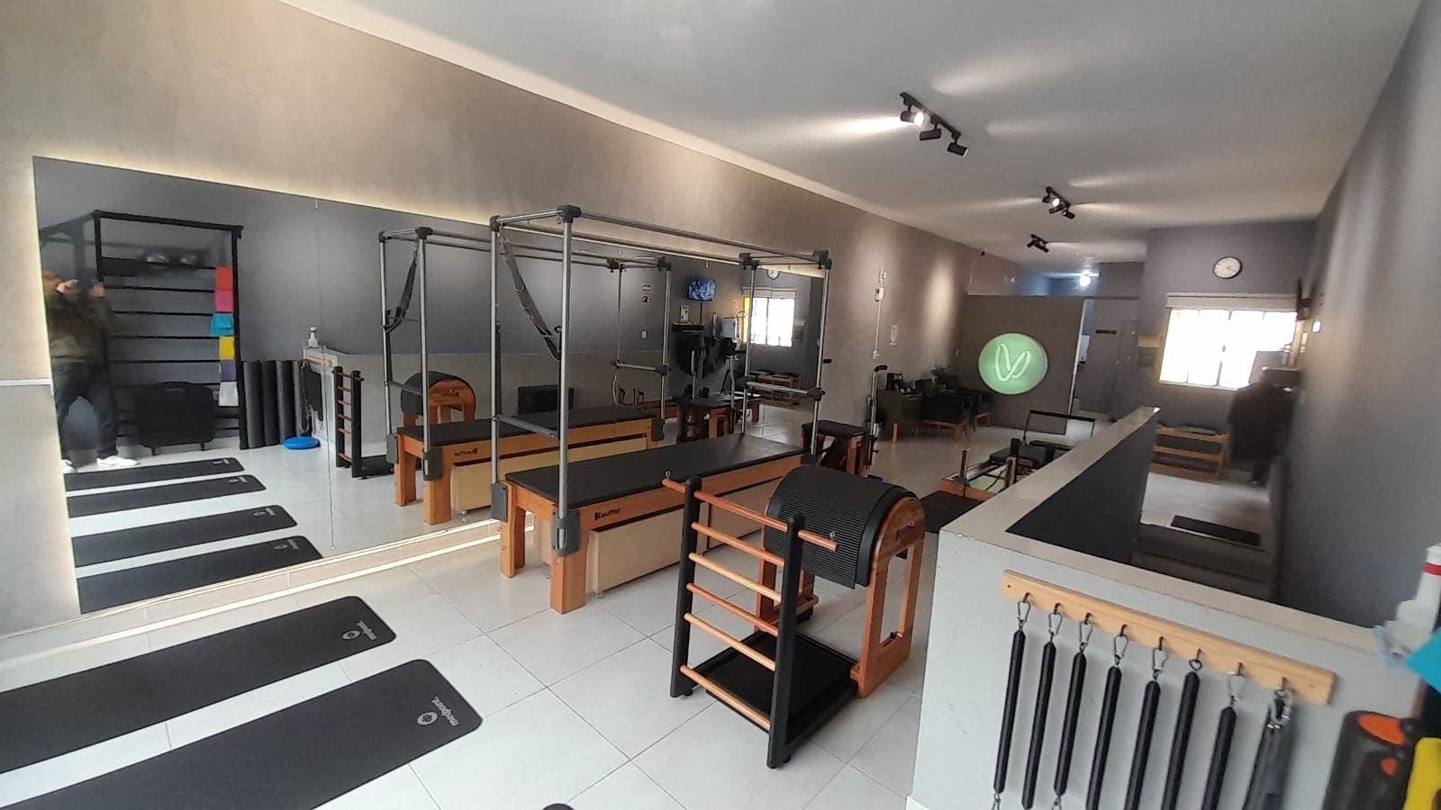 Sala principal do Voll Pilates Aclimação com aparelhos completos e o V iluminado ao fundo