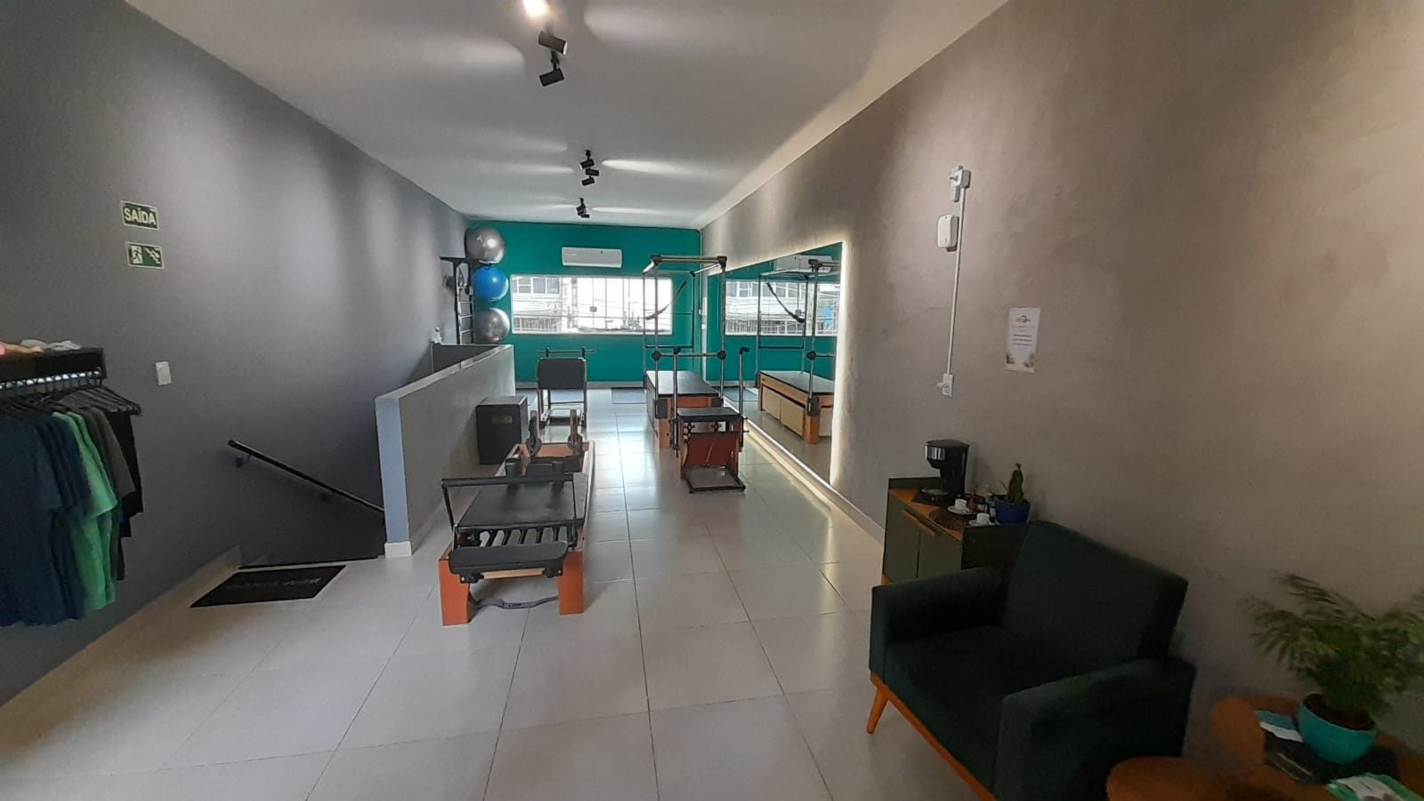 Ambiente acolhedor do Voll Pilates Aclimação com aparelhos, parede verde e área de espera