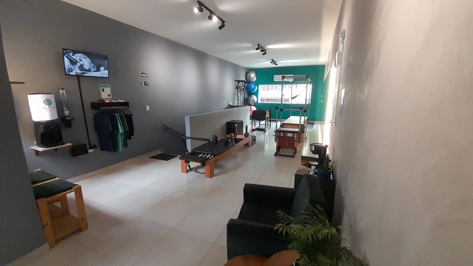 Área de espera com poltronas, cafeteria e parede verde do estúdio