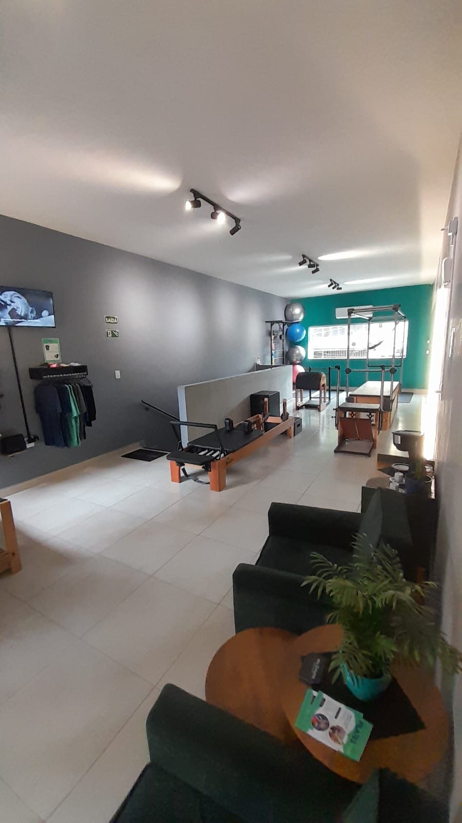 Área de espera do estúdio com poltronas, plantas e parede verde